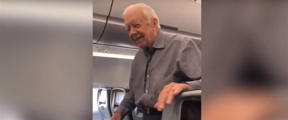 Jimmy Carter prochází letadlo a zdraví cestující.