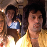 John Deacon (vzadu) a Freddie Mercury bhem soukromho letu.