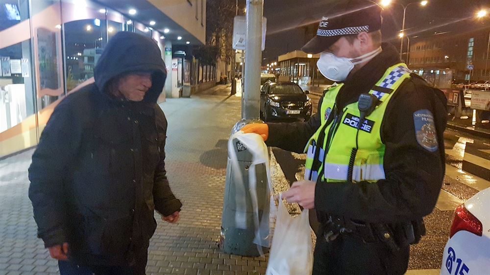 Policisté rozdávají rouky bezdomovcm.