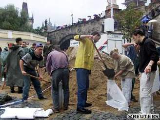 Dobrovolníci plní pytle pískem