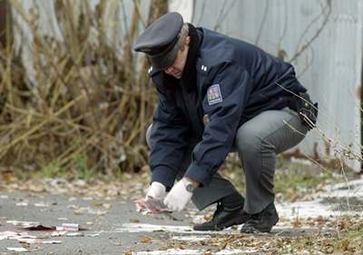 Policista sbírá bankovky, které v Milovicích odhodil lupi.