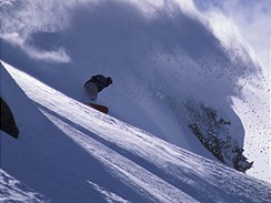 Snowboardista v ternu, v pozad lavina
