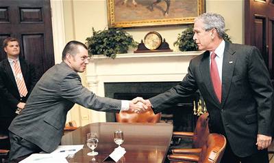 Redaktor MF DNES Teodor Marjanovi se zdraví s Georgem Bushem. Musí se k prezidentovi naklonit pes stl - Bush podává ruku ponkud zdaleka