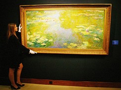 Pracovnice Christie's s obrazem Jezrko s leknny od Claude Moneta