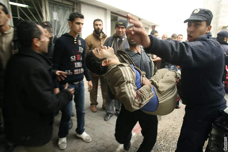 Palestinci nesou mladíka zranného pi izraelském útoku do nemocnice.