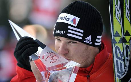 výcar Dario Cologna líbá trofej pro vítze Tour de Ski