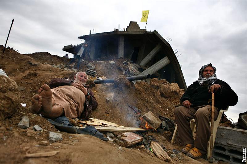 Palestinci se zahívají na míst, kde stávaly jejich domy v táboe Dabália na severu Gazy.  (20. leden 2009)