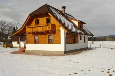 Hladký bílý pás soklu a nároí zajímav kontrastují s roubenou strukturou