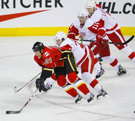 Olli Jokinen z Calgary ujídí a za ním se ene kohorta hokejist Detroitu.