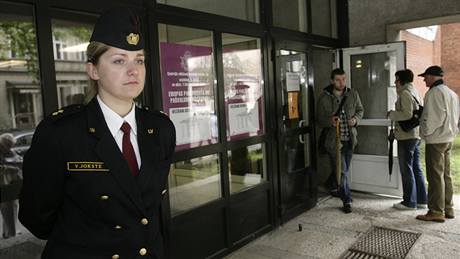 Policistka hlídá v lotyské Rize vstup do volební místnosti (6. ervna 2009)