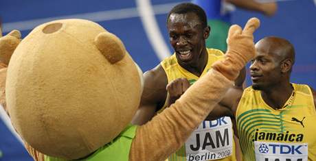 Asafa Powell (vpravo) a Usain Bolt oslavují tafetový triumf v cíli s maskotem ampionátu
