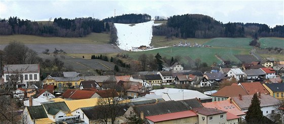 V Olenici po oblev nad zelenými kopci záí umle zasnená sjezdovka.