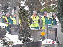 Pracovnci Technickch slueb msta Slavkova prolapvaj cestiky mezi zasnenmi nhrobky mstnho hbitova