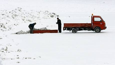 Na jihu ech pipadlo dalích piblin 5 cm snhu. Mui vykládají odklizený sníh na náplavku eskobudjovického Velkého jezu (26. ledna 2010)