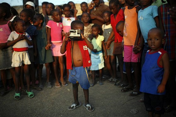 Haitský chlapec fotí v provizorním táboe pro peiví v Port-au-Prince