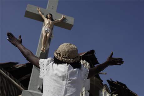 ena stojí ped kíem na Haiti a modlí se v den výroí jednoho msíce od zemtesení