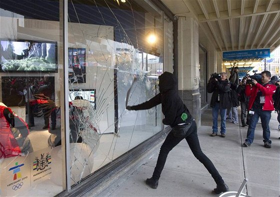 VANDALISMUS. Jeden z demonstrant pímo ped oima kameraman rozbíjí výlohu obchodu s olympijským obleením.