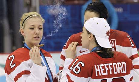 Kanadsk hokejistky oslavuj olympijsk triumf a dvaj si vtzn doutnek.
