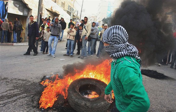 Palestinec zapaluje pneumatiku pi protestech v Hebronu