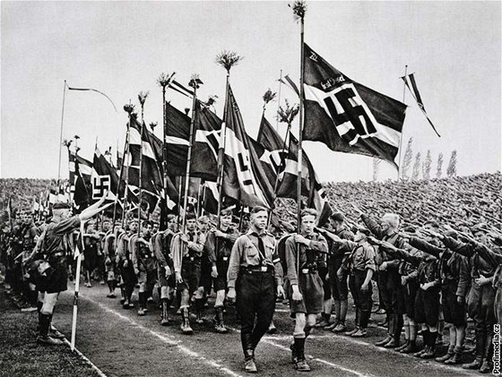 Mladí Nmci, takzvaní Hitlerjugend, hajlují nacistickým vlajkám. (1933)
