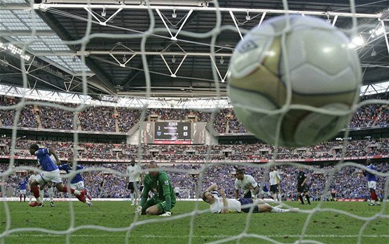UKLOUZNUTÍ A GÓL. Tottenhamský obránce Dawson padá na trávník ve Wembley a Piquionne z Portmsouthu (vlevo) stílí gól. Kdo si lépe poradí s terénem, vyhraje.