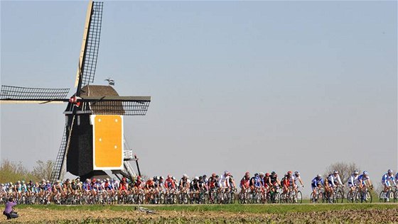 Cyklisté na trati závodu Amstel Gold race míjejí vtrný mlýn. 