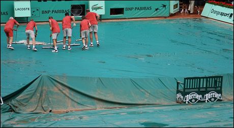 Roland Garros - Po deti je nejprve nutn odehnat vodu z ochrannch fli. Teprve potom je mon kurt odkrt.