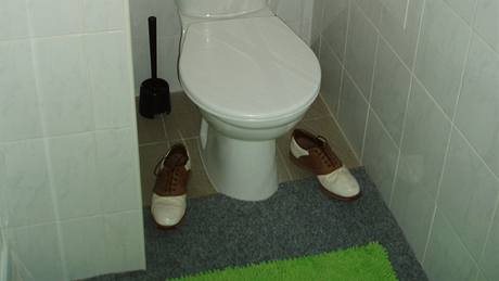 Aby se koberec na toalet neroloval, zatíil jej majitel starými botami na golf