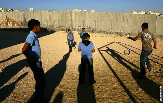 Mladí palestintí chlapci hrají fotbal na kolním hiti v Jeruzalém u hraniní zdi s Izraelem.