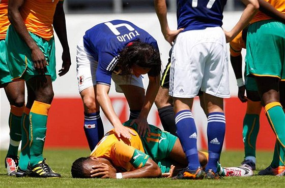 Didier Drogba se svíjí bolestí, japonský stoper Tulio Tanaka se mu omlouvá.