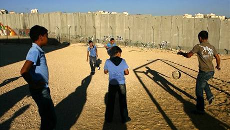 Mladí palestintí chlapci hrají fotbal na kolním hiti v Jeruzalém u hraniní zdi s Izraelem.