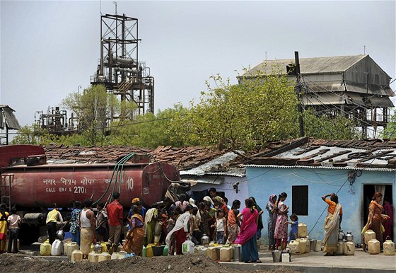 Indické eny v Bhópálu nabírají vodu, v pozadí továrna spolenosti Union