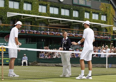 PED ZPASEM. Ped utknm ve Wimbledonu se zdrav s rozhod John Isner (vlevo) a Thiemo De Bakker.