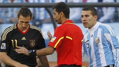 Ravan Irmatov eí situaci, kdy nmecký útoník Miroslav Klose (vlevo) fauloval argentinského záloníka Javiera Mascherana. Pihlíí Nicolas Otamendi (vpravo).