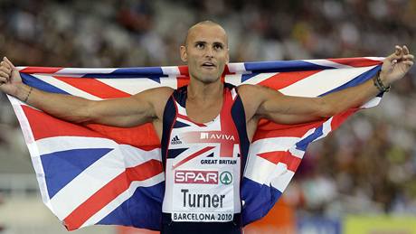 Brit Andy Turner s vlajkou slaví zlatou medaili ze závodu na 110 m pekáek.