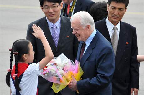 Jamese Cartera vítá na letiti v Pchjongjangu dívka s erveným átkem (25. srpna 2010) 