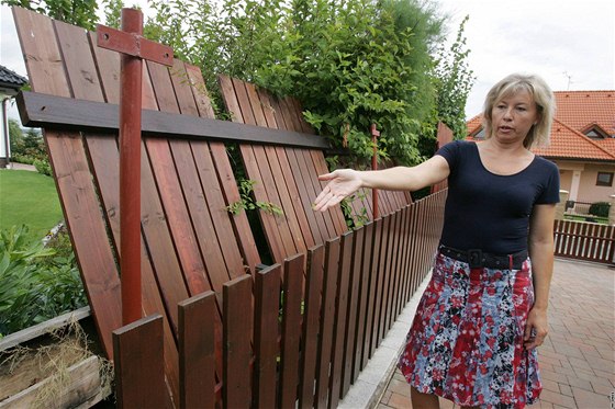 Monika Sovová ze lapanic ukazuje vyvrácený plot, který si její sousedé Grochovi postavili naerno.