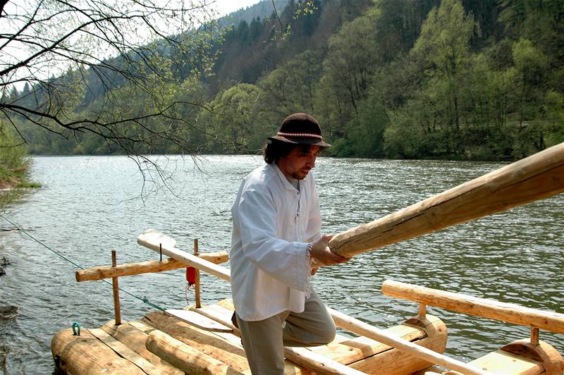 Slovensko, splouvání Oravy na voru. Jánko árfy jde uloit pední veslo na své místo