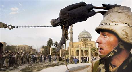 Americký voják sleduje strení Saddámovy sochy v iráckém Bagdádu. (9. dubna