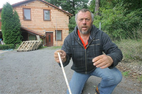 Ladislav Suchánek ukazuje jakou ástí dm pesahuje na pozemek msta.