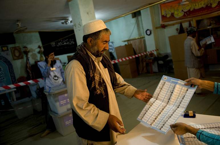 Afghánec dostává v kábulské volební místnosti hlasovací lístek se jmény kandidát do parlamentu.