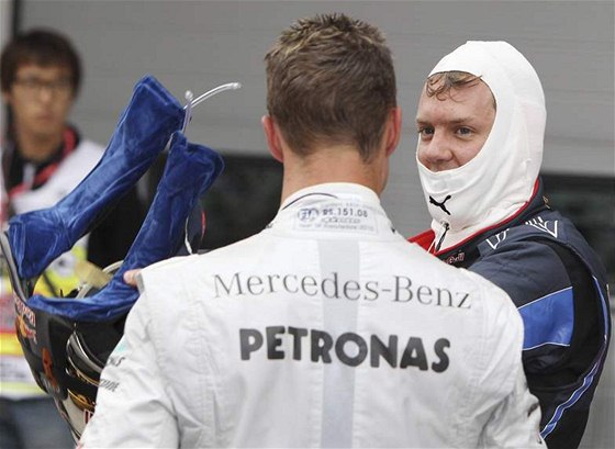 Michael Schumacher (zády) gratuluje Sebastianu Vettelovi k vítzství v kvalifikaci na Velkou cenu Koreje.