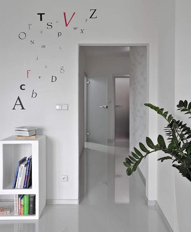 Lesklá podlaha vytváí zajímavý zrcadlový efekt. Bílé stny jsou dekorovány tapetami (Lars Kontzen) a nálepkami ve tvaru písmen (Wise Decor)