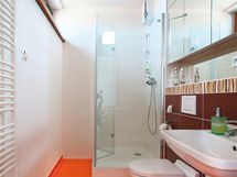 Koupelna u lonice kombinuje oranovou podlahu a bl i hnd obklady s relifnmi "vlnkami"