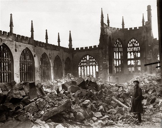 Mu stojí uprosted sutin rozbombardované katedrály v Coventry. (listopad 1940)