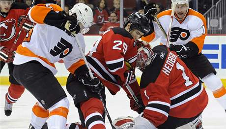 Branká New Jersey Devils Johan Hedberg se snaí lapakou pikrýt puk v zápase proti Philadelphii Flyers.