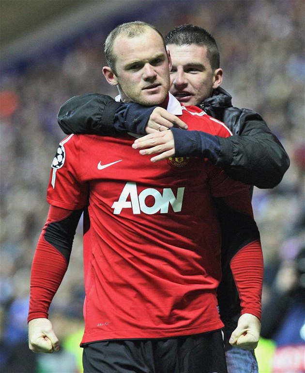 NEEKANÝ GRATULANT. Útoník Wayne Rooney z Manchesteru United slaví gól v utkání Ligy mistr proti Glasgow Rangers. Pi tom se na nj vrhl jeden z fanouk.