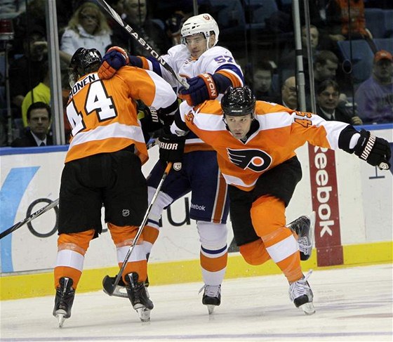 Centr New Yorku Islanders Blake Comeau se ocitl v presu Kimmo Timonena (vlevo) a Jodyho Shelleyho z Philadelphie. 