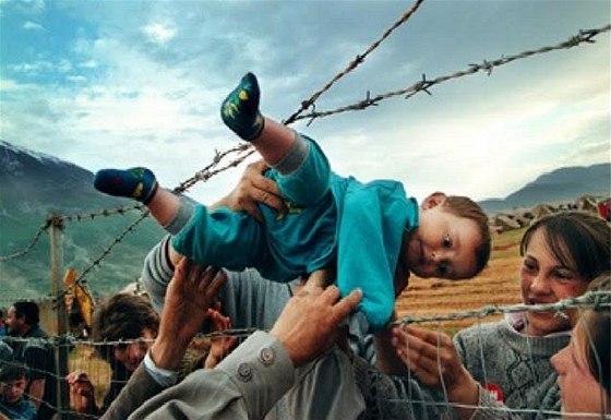 Shalovi, kteí utekli ped etnickými istkami z Kosova, podávají skrz ostnatý drát uprchlického tábora v Albánii prarodim dvouletého syna Akima. (3. kvtna 1999)