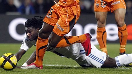 PO ČTYŘECH. Bafe Gomis, útočník Lyonu (na zemi), se snaží probít se s míčem mezi obránci Lorientu PO ČTYŘECH. Bafe Gomis, útočník Lyonu (na zemi), se snaží probít se s míčem mezi obránci Lorientu
